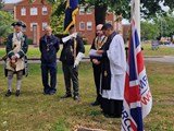 Dignitaries congregate around a flagpole for a flag-raising ceremony